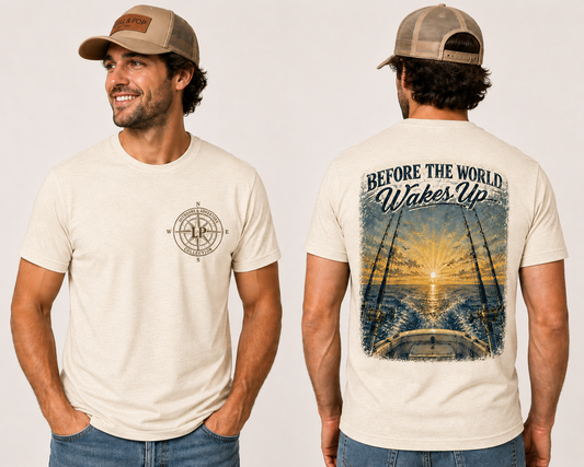 Man wearing the Before the World Wakes Up graphic tee featuring a vintage sunrise fishing scene on a peaceful lake.
