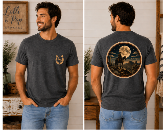 Man wearing the Moonlit Journey graphic tee featuring a cowboy on horseback overlooking a glowing full moon from a rugged cliff.